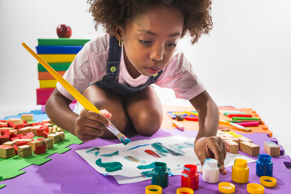 A young girl concentrating on painting at a studio table