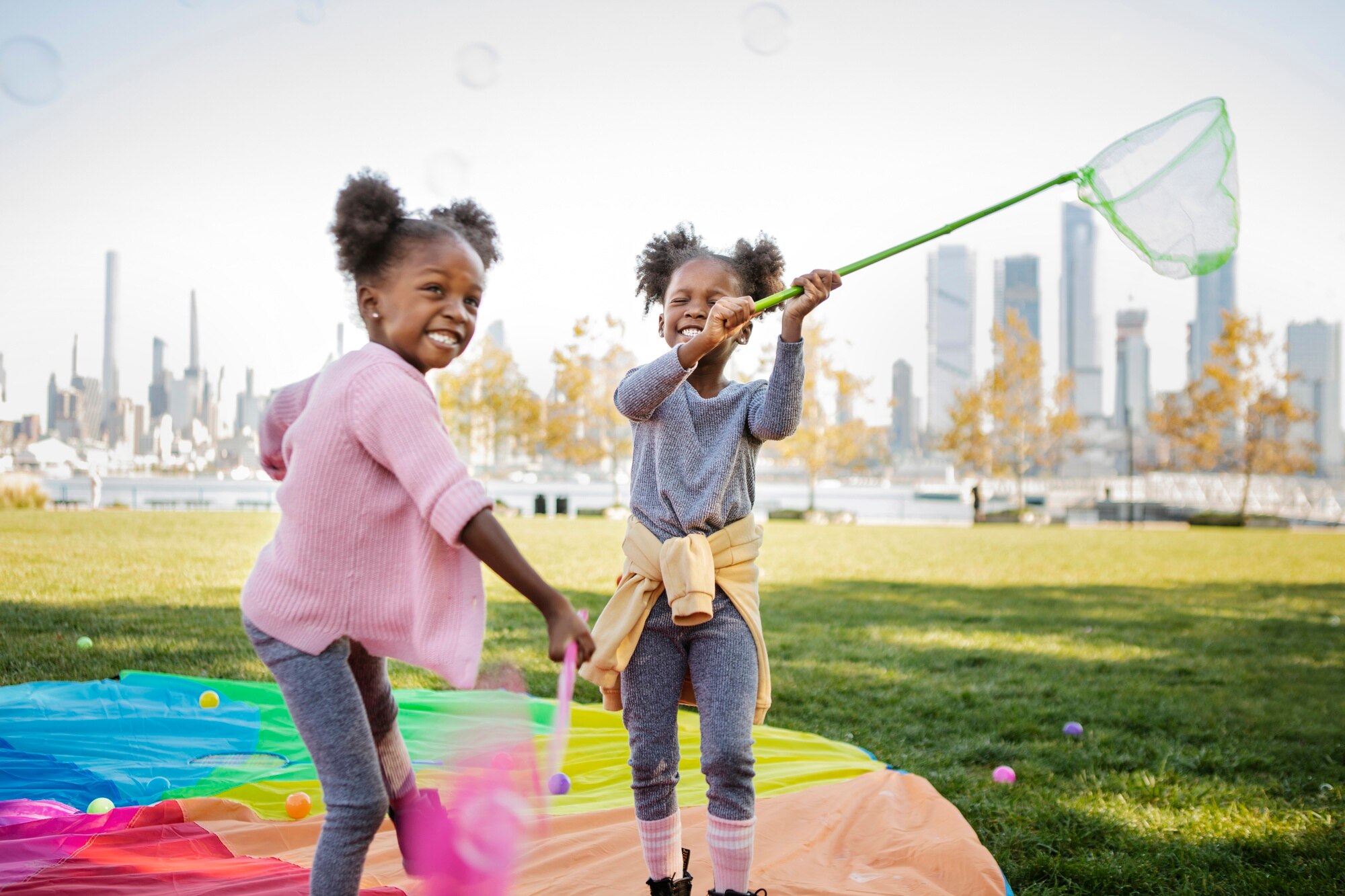 Two young girls laughing and playing outdoors in golden afternoon light